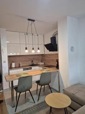 a kitchen with a table and chairs in a room at Muki Oaza Apartman in Tuzla