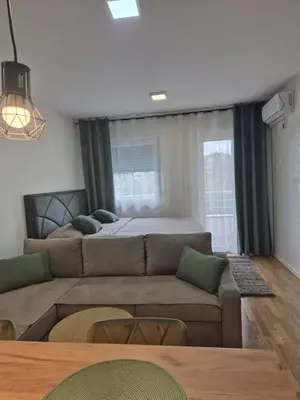 a living room with a couch and a bed at Muki Oaza Apartman in Tuzla