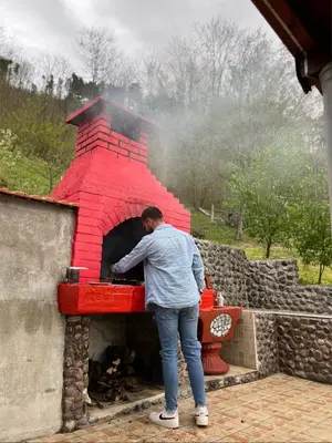 a man standing in front of a brick oven at Vikendica Krivaja sa bazenom i privatnom plažom in Zavidovići