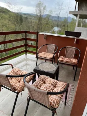 a patio with three chairs and a table on a balcony at Vikendica Krivaja sa bazenom i privatnom plažom in Zavidovići