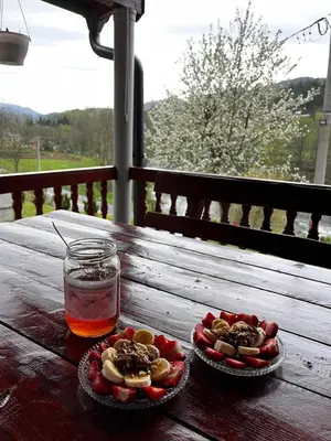 a wooden table with two plates of food and a drink at Vikendica Krivaja sa bazenom i privatnom plažom in Zavidovići