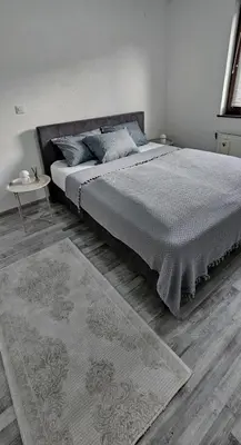 a bedroom with a large bed and a rug at Apartman STARI GRAD in Bihać