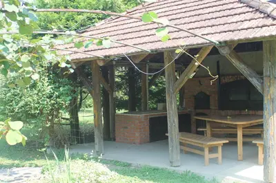 a wooden pavilion with a table and a bench at The River House in Lohovo