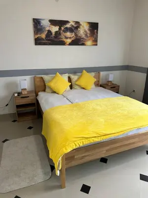 a bedroom with a bed with a yellow blanket at Studio Apartman Orhideja in Sanski most