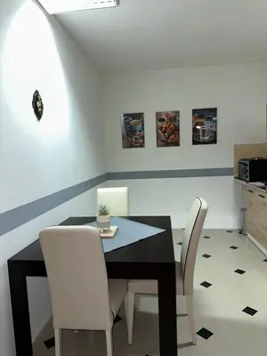 a dining room with a black table and white chairs at Studio Apartman Orhideja in Sanski most