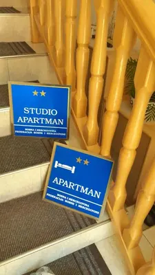 two signs sitting on the floor next to a wooden staircase at Studio Apartman Orhideja in Sanski most