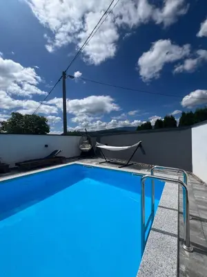 a blue swimming pool with a chair next to a wall at Melissa luxury Apartment in Bijelo Brdo