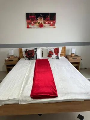 a large white bed with a red blanket on it at Apartman Orhideja za 4 osobe in Sanski most