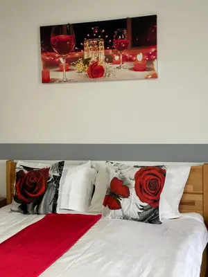 a bed with red roses on it with glasses of wine at Apartman Orhideja za 4 osobe in Sanski most