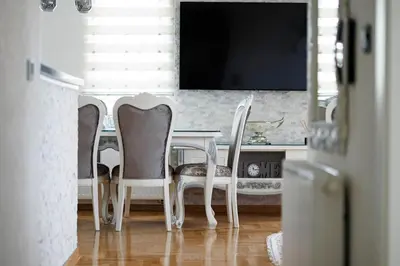 a dining room table with three chairs and a television at Apartman Luxury Kiseljak in Kiseljak