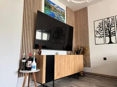 a living room with a television and a table with wine bottles at Apartman N&N in Bihać