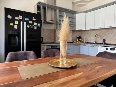 a kitchen with a wooden table with a vase with dry grass at Apartman N&N in Bihać