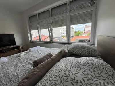 a bedroom with a bed and a large window at Dora Apartman in Banja Luka