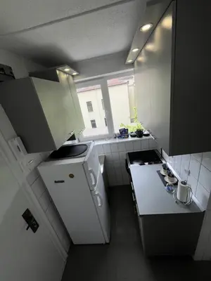 a small kitchen with white appliances and a window at Dora Apartman in Banja Luka