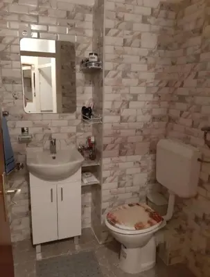 a bathroom with a toilet and a sink and a mirror at Apartman NAFO in Bihać