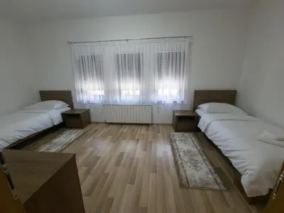 a room with two beds and a window and wooden floors at Milky Way in Bihać
