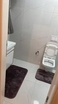 a white bathroom with a toilet and a sink at Stan Tešanj in Tešanj