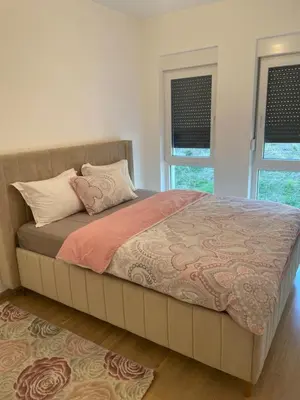a large bed in a room with two windows at Stan Tešanj in Tešanj