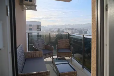 a balcony with chairs and a view of a city at Hedonist Garden Luxury Apartments in Doboj