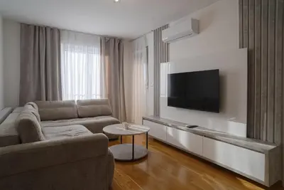 a living room with a couch and a flat screen tv at Hedonist Garden Luxury Apartments in Doboj