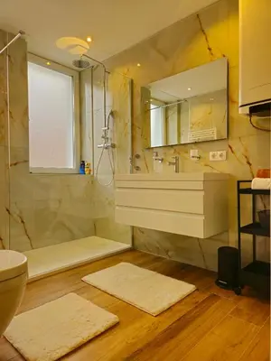a bathroom with a shower and a sink and a mirror at Apartman Trg 892 in Livno