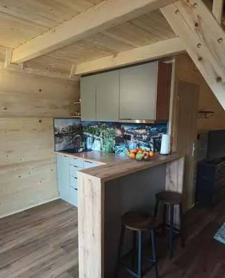 a kitchen with a counter and stools in a cabin at Cottage MIRNI RAJ in Jajce