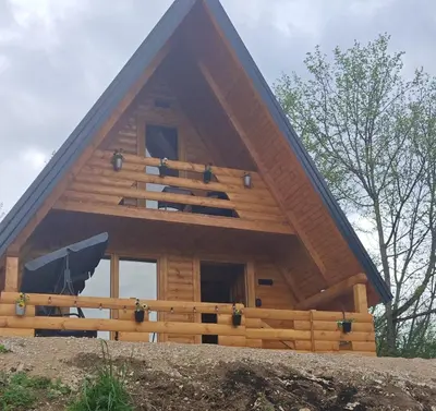 a large wooden house with a pitched roof at Cottage MIRNI RAJ in Jajce