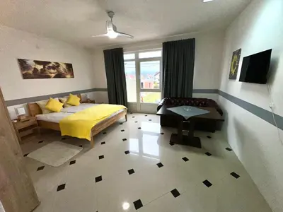 a bedroom with a yellow bed and a window at Apartmani Orhideja za 2 osobe studio in Sanski most
