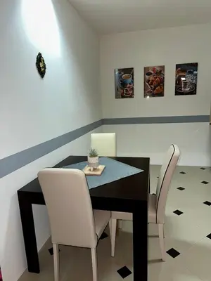 a dining room with a black table and white chairs at Apartmani Orhideja za 2 osobe studio in Sanski most