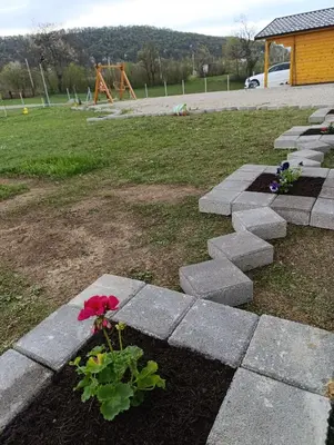 a flower in a garden with a playground in the background at Vikendica Ajlin in Bihać