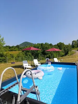 a swimming pool with two slides and chairs and umbrellas at Vikendica Ajlin in Bihać