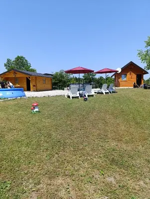 a yard with chairs and umbrellas and a house at Vikendica Ajlin in Bihać