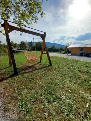 an empty swing in a field with a building at Vikendica Ajlin in Bihać