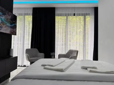 a bedroom with a bed with two chairs and a large window at Villa Happiness in Banja Luka