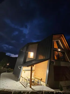 a house with a black roof and two benches at Luxury Villa Mašić - 2 in Bugojno