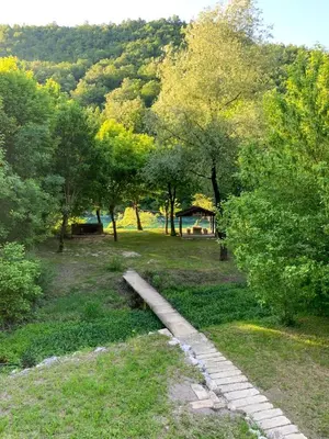 a stone path in a park with trees and a building at Unea House in Bihać