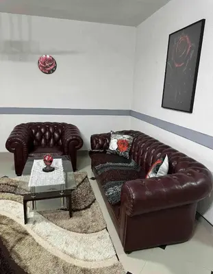 a living room with two leather couches and a table at Apartmani Orhideja za 4 osobe in Sanski most