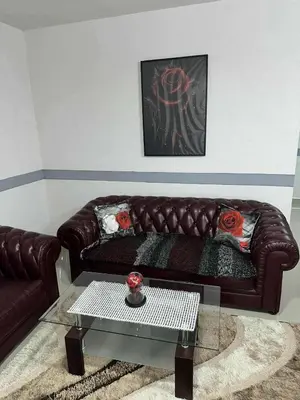 a brown leather couch in a living room with a table at Apartmani Orhideja za 4 osobe in Sanski most