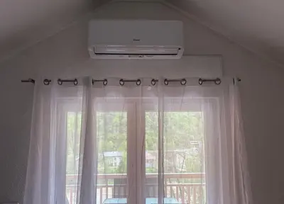 a window with white curtains and a air conditioner at Apartmani D&D 4 in Jajce