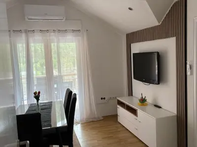 a dining room with a table and a tv and a window at Apartmani D&D 4 in Jajce