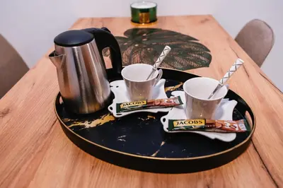 a plate with a coffee pot and two cups on a table at Apartment Vukeljic in Doboj