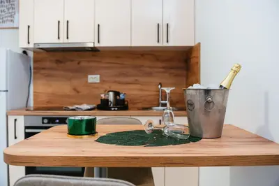 a kitchen counter with a wooden table with a bucket at Apartment Vukeljic in Doboj