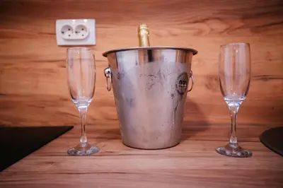 two wine glasses and a bucket with a bottle in it at Apartment Vukeljic in Doboj