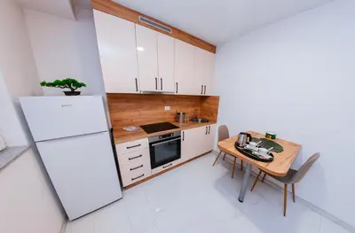 a kitchen with a table and a white refrigerator at Apartment Vukeljic in Doboj