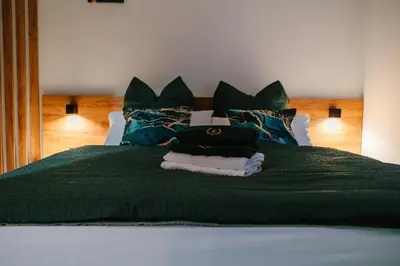 a bed with a green blanket and pillows on it at Apartment Vukeljic in Doboj