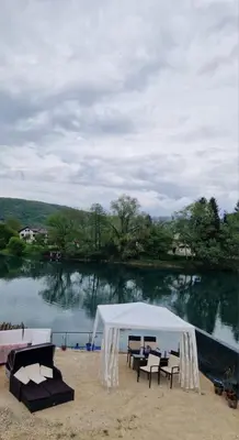 a white tent on the beach next to a lake at Apartman Villa E&M in Bihać