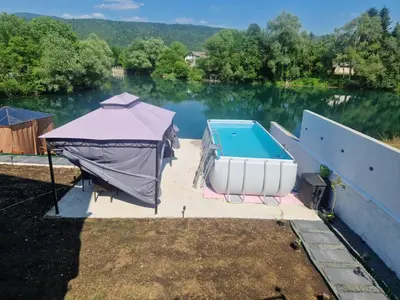 a swimming pool with a tent next to the water at Apartman Villa E&M in Bihać