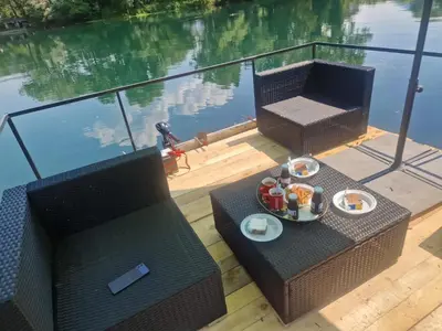 a table with food on it next to a body of water at Apartman Villa E&M in Bihać