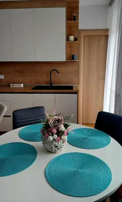 a table with four blue plates and a vase of flowers at Banjaluka Centar1 in Banja Luka