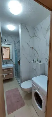 a bathroom with a toilet and a sink and a washing machine at Banjaluka Centar1 in Banja Luka